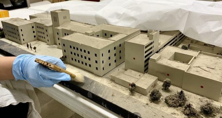 A staff member from the U.S. Army Airborne and Special Operations Museum works on cleaning this model (in preparation for the restoration process) that was used to plan and prepare for Operation Eagle Claw, the mission to rescue American hostages at the U.S. Embassy in Tehran.