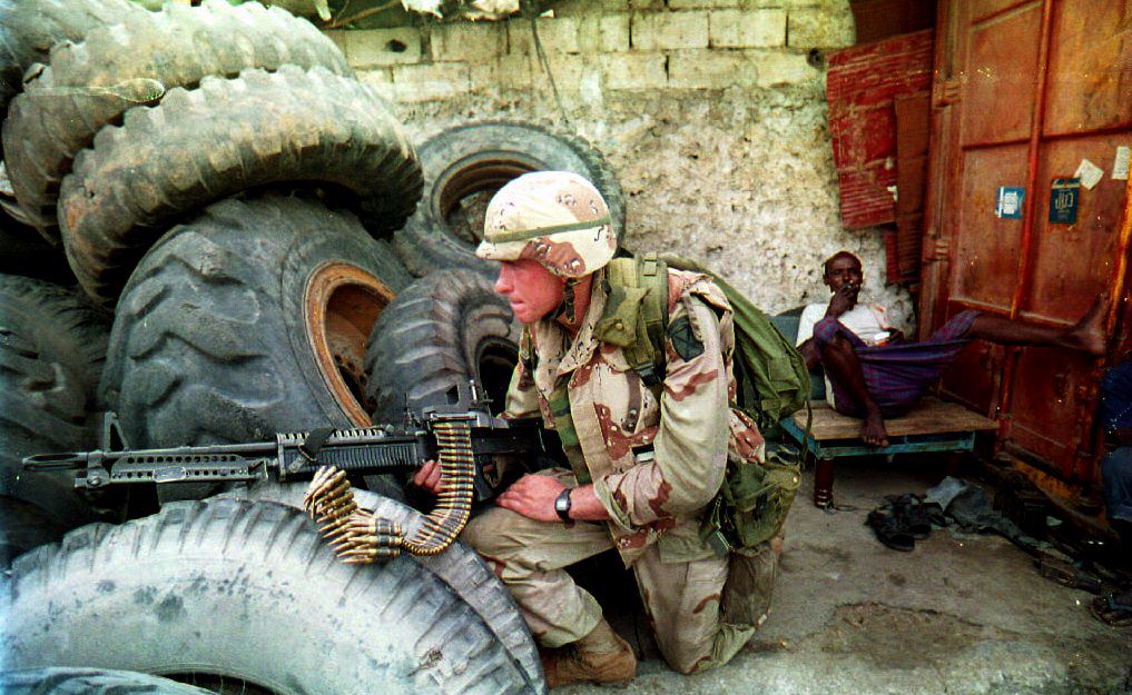 A Soldier takes cover beside a stack of tires.
