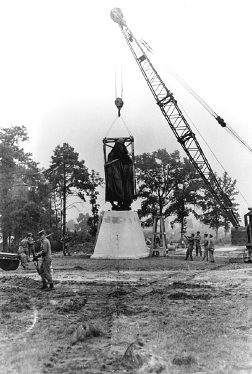 Post engineers using a crane to hoist the statue onto its pyramid base