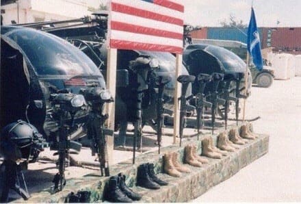 A memorial arrangement of helmets, rifles and boots beneath an American flag.