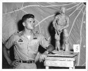 Specialist Janis Krisans standing with one of the finished clay miniatures